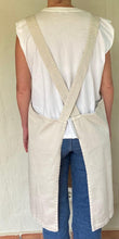 Cargar imagen en el visor de la galería, delantal de loneta beige con la espalda cruzada y con bolsillos de valencia te quiero vista de espaldas